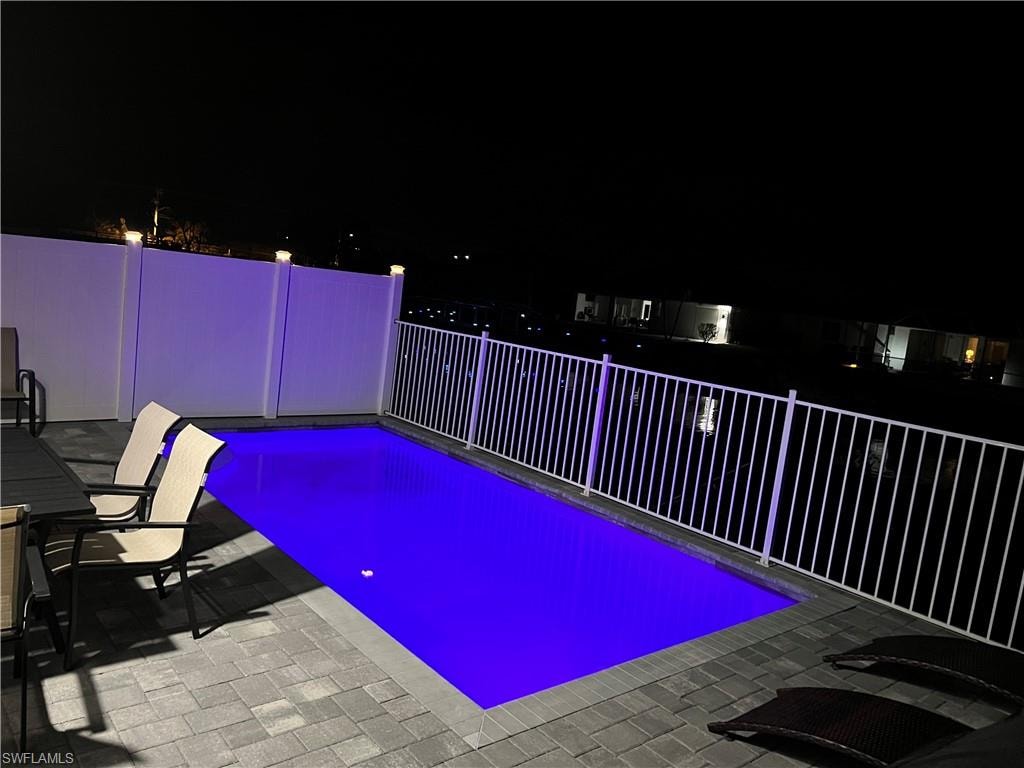 Pool at night featuring a patio