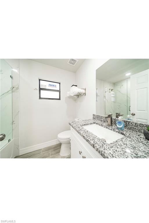 Bathroom with vanity, toilet, and a shower with shower door
