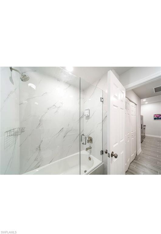 Bathroom with tiled shower / bath and hardwood / wood-style floors