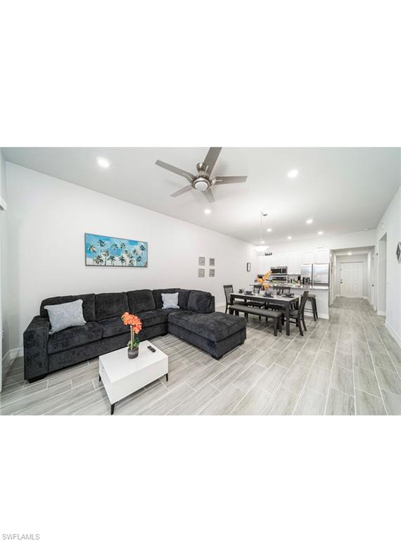 Living room with light hardwood / wood-style flooring, ceiling fan, and vaulted ceiling