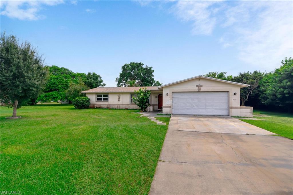 Ranch-style home featuring a garage and a front lawn