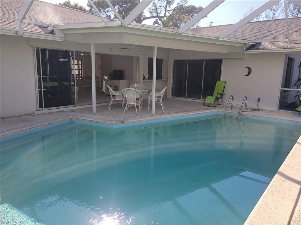 View of pool with a lanai, ceiling fan, and a patio area