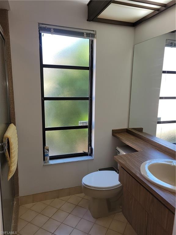 Bathroom featuring vanity, plenty of natural light, tile patterned floors, and toilet