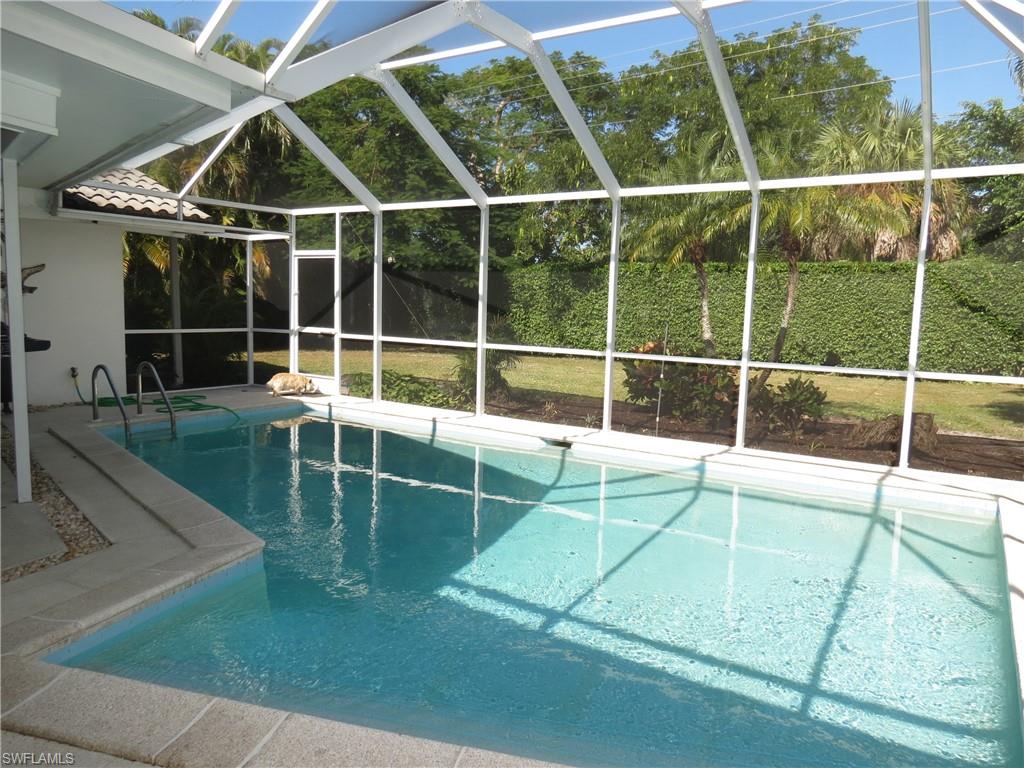 View of swimming pool featuring glass enclosure and a patio