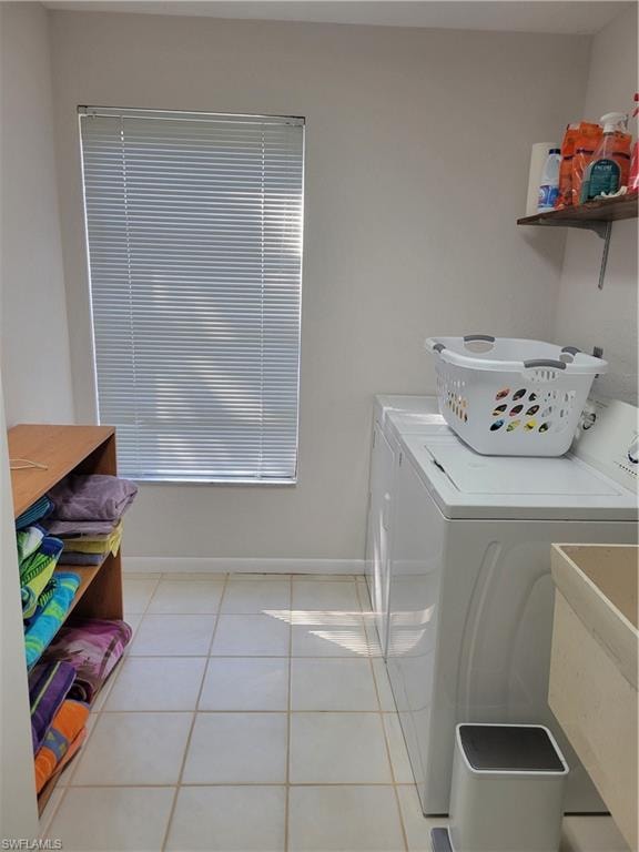 Laundry room featuring light tile patterned flooring, washer and clothes dryer, and sink