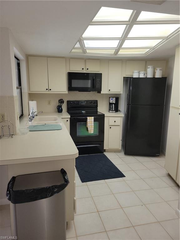 Kitchen with sink, refrigerator, black range with electric stovetop, kitchen peninsula, and cream cabinetry