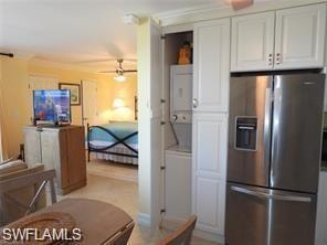 Kitchen featuring stacked washer and clothes dryer, white cabinetry, ceiling fan, and stainless steel fridge
