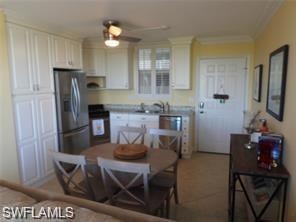 Kitchen with ceiling fan, ornamental molding, white cabinetry, stainless steel refrigerator with ice dispenser, and black stove