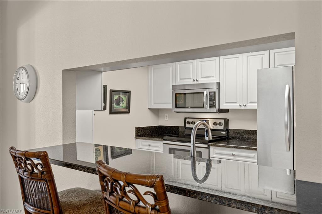 Kitchen featuring white cabinets, dark stone countertops, appliances with stainless steel finishes, and sink