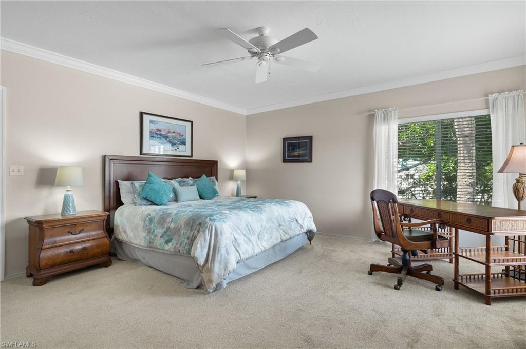 Bedroom with ceiling fan, ornamental molding, and carpet