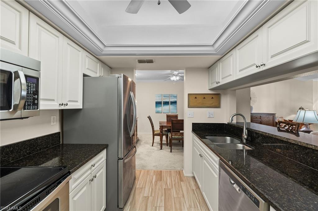 Kitchen with white cabinets, ceiling fan, appliances with stainless steel finishes, and sink