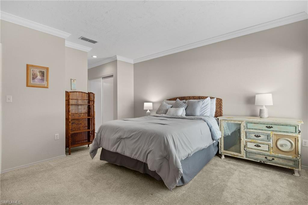 Bedroom featuring light colored carpet, a closet, and ornamental molding