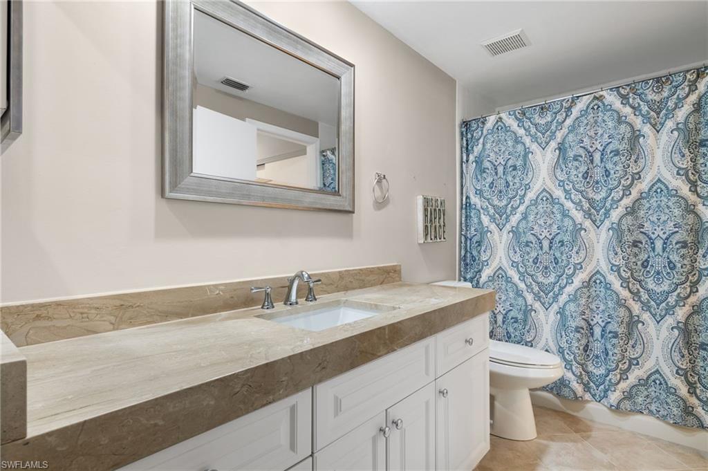 Bathroom with a shower with curtain, vanity, toilet, and tile patterned floors