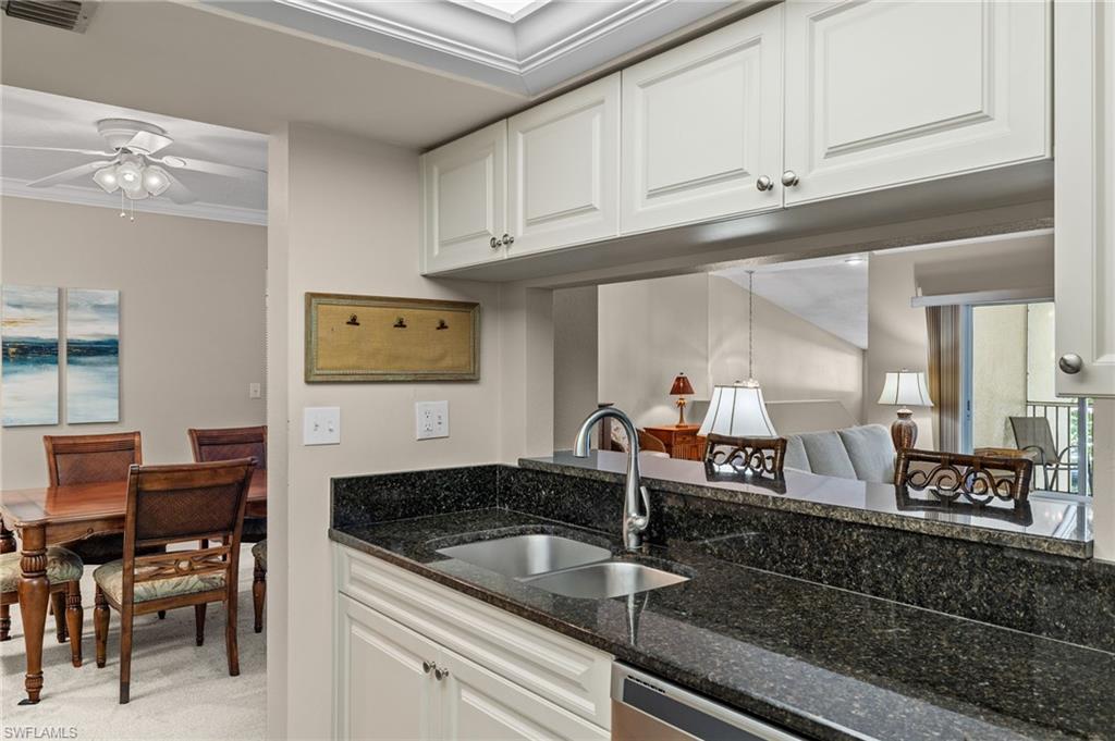 Kitchen with white cabinetry, crown molding, ceiling fan, dark stone counters, and sink