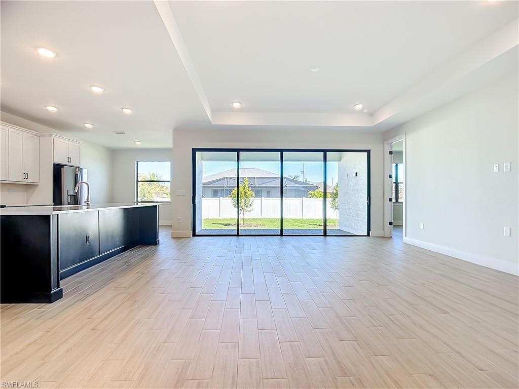 Kitchen with light wood-type flooring, stainless steel fridge, and white cabinetry