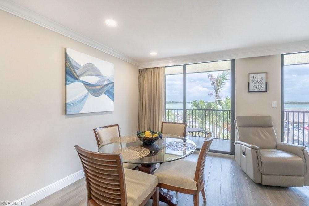 Dining area featuring light hardwood / wood-style flooring, floor to ceiling windows, ornamental molding, and a water view
