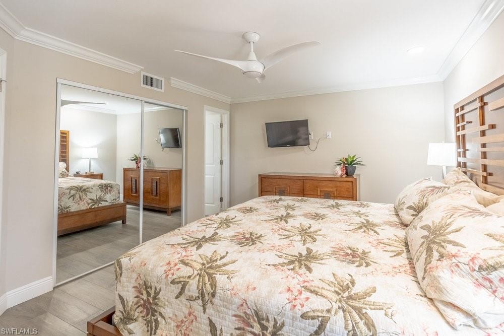 Bedroom with ceiling fan, a closet, crown molding, and light hardwood / wood-style floors
