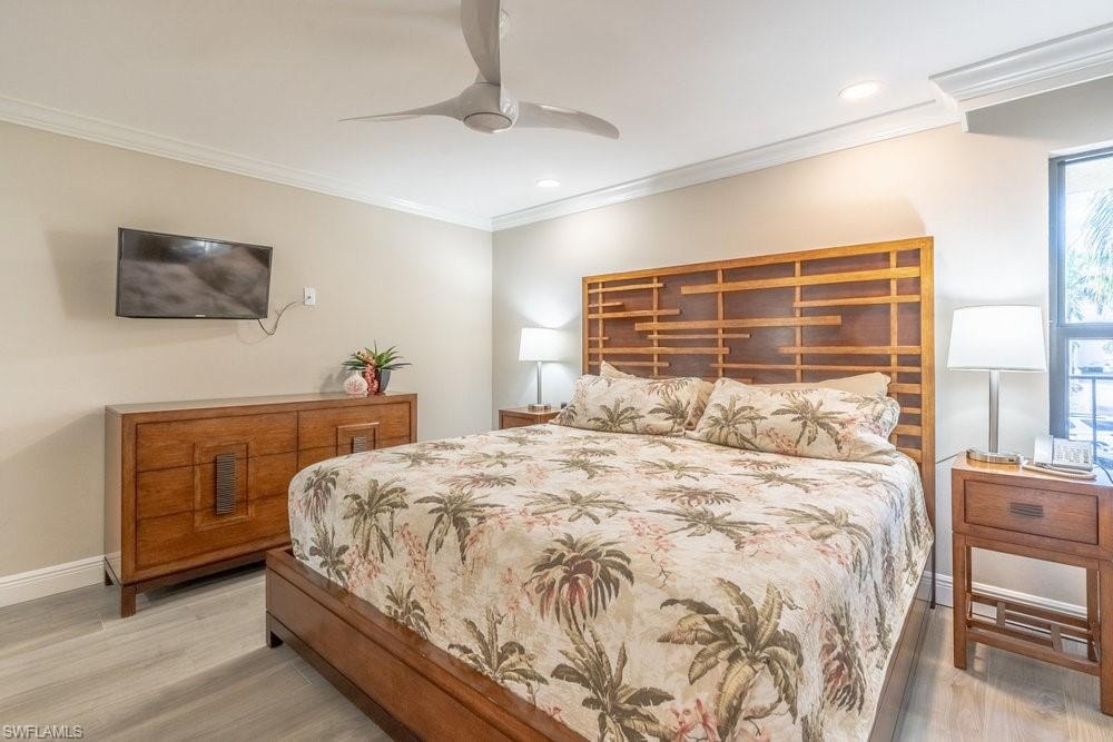Bedroom with light wood-type flooring, ceiling fan, and crown molding