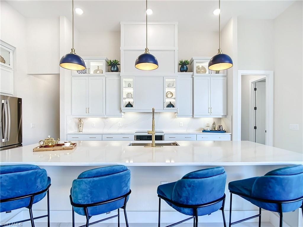 Kitchen featuring hanging light fixtures, stainless steel fridge, and white cabinets