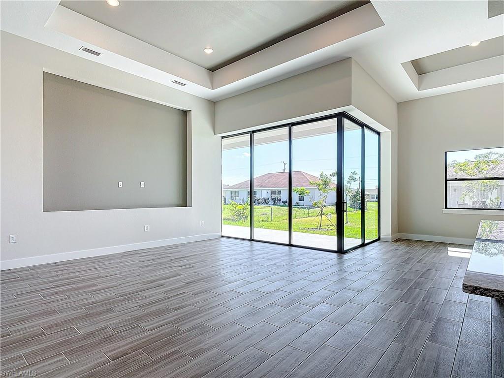 Spare room with a raised ceiling, baseboards, wood tiled floors, and recessed lighting