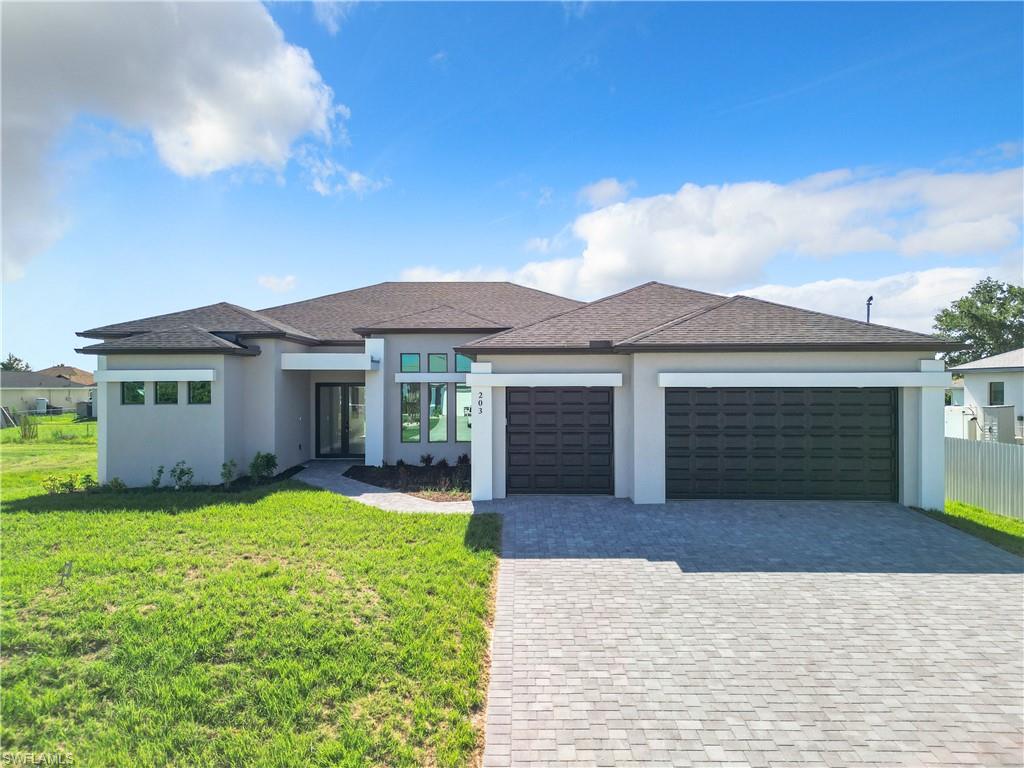 Prairie-style house with an attached garage, decorative driveway, stucco siding, and roof with shingles