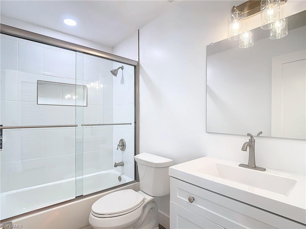 Full bathroom featuring enclosed tub / shower combo, vanity, and toilet