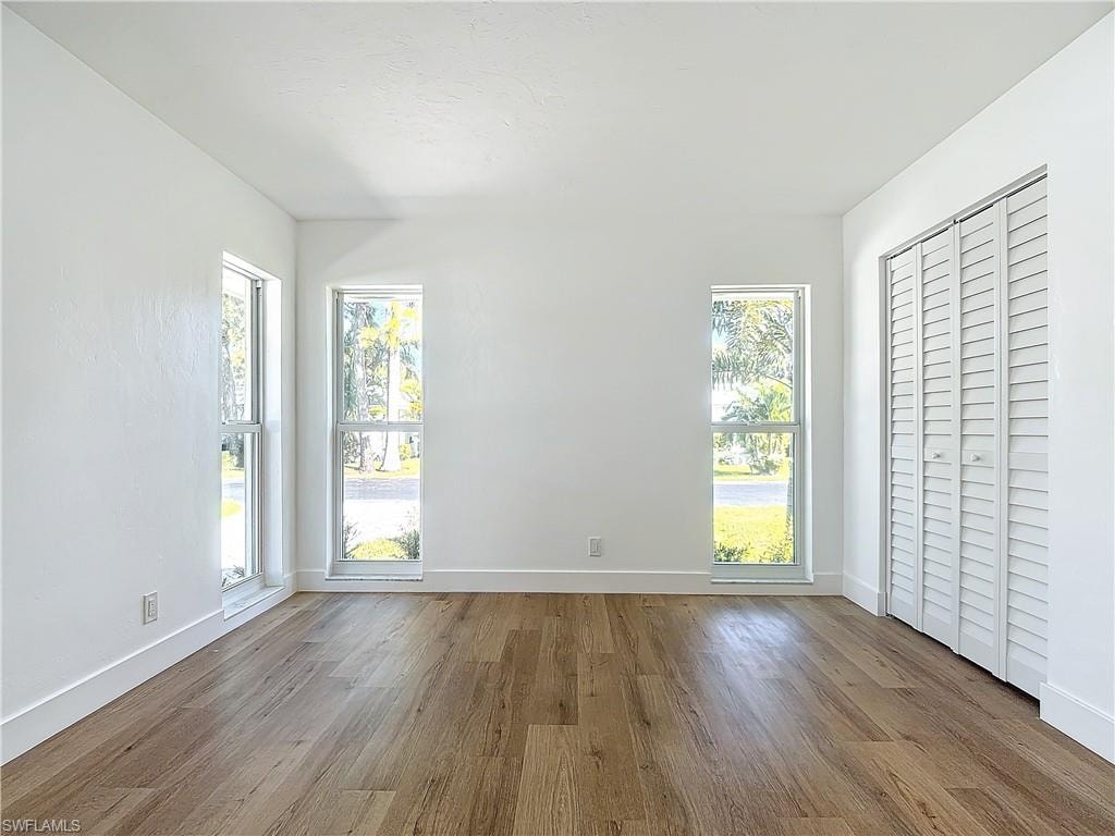 Unfurnished bedroom with light hardwood / wood-style floors and multiple windows