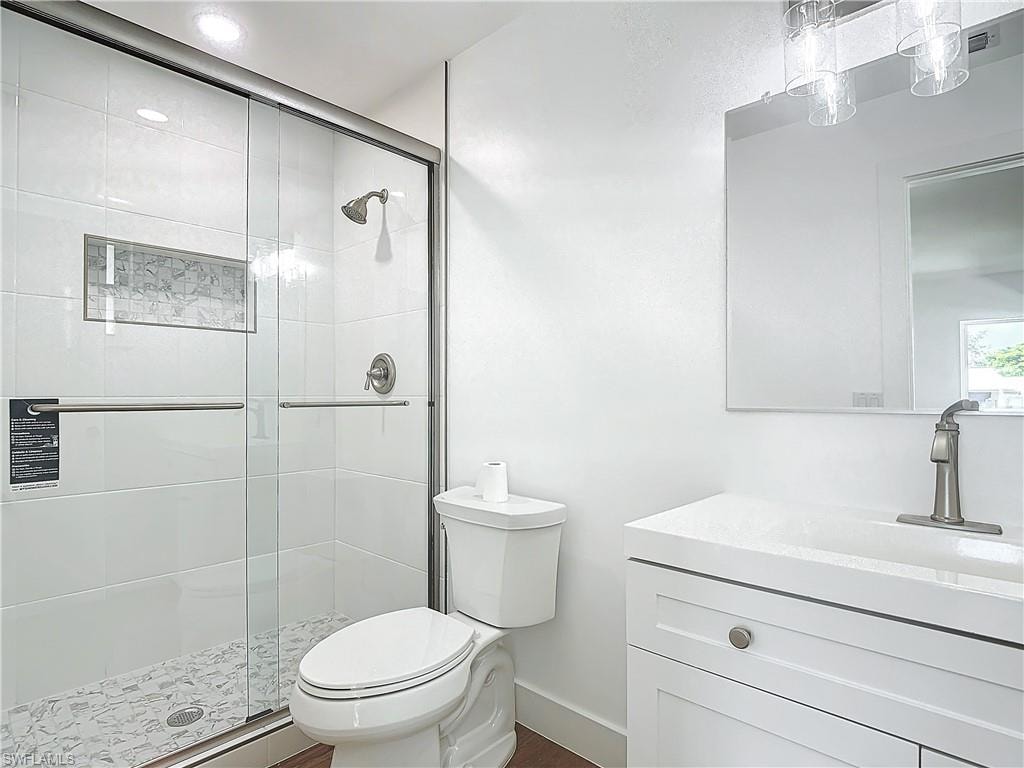 Bathroom featuring a shower with door, vanity, and toilet