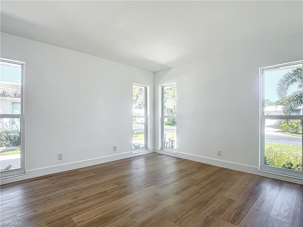 Unfurnished room featuring dark hardwood / wood-style floors and a wealth of natural light
