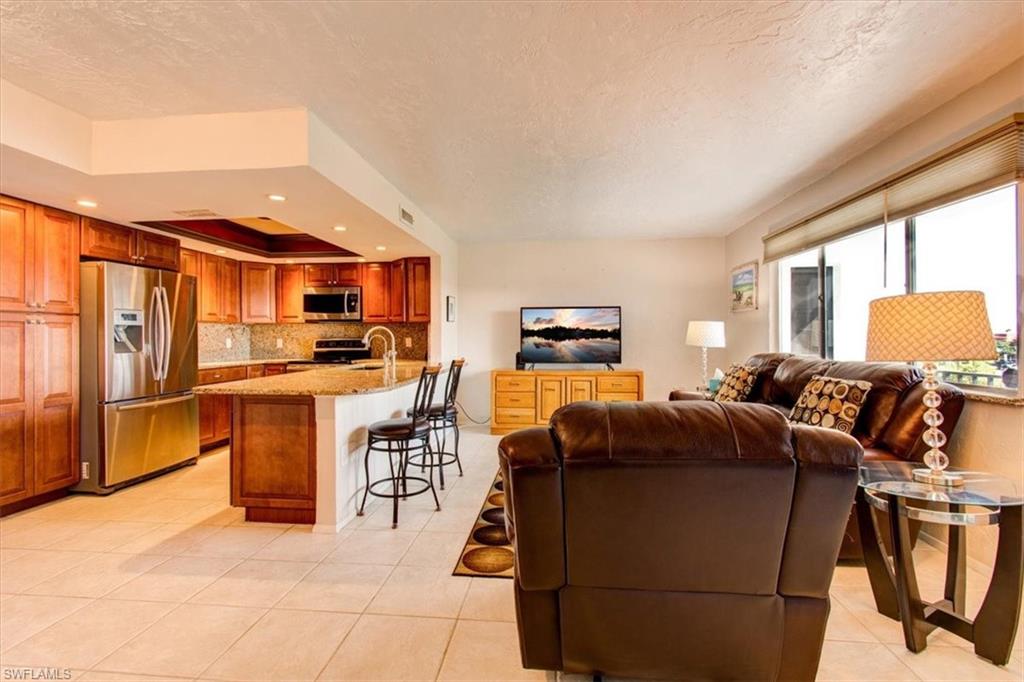 Tiled living room with a textured ceiling, a tray ceiling, and sink