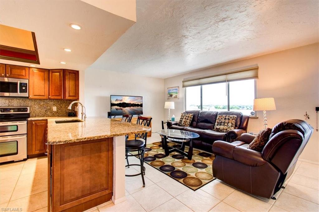 Kitchen featuring light tile patterned floors, sink, kitchen peninsula, stainless steel appliances, and a kitchen bar