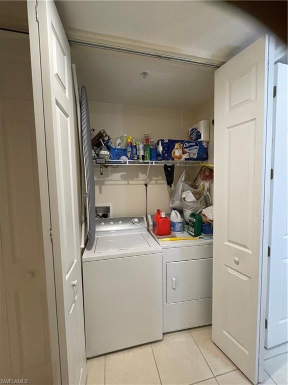 Clothes washing area featuring light tile patterned flooring and washer and dryer
