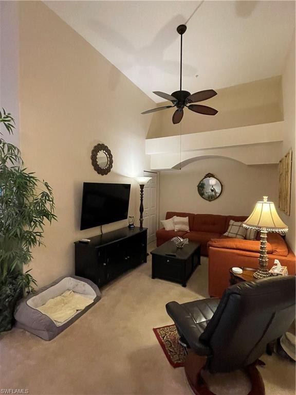 Den with light carpet, high vaulted ceiling, and ceiling fan