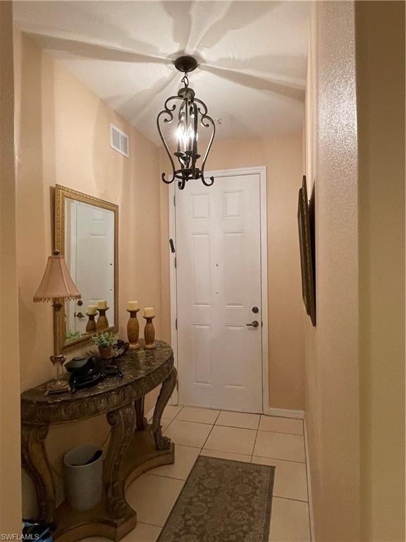 Doorway to outside with a chandelier and light tile patterned flooring