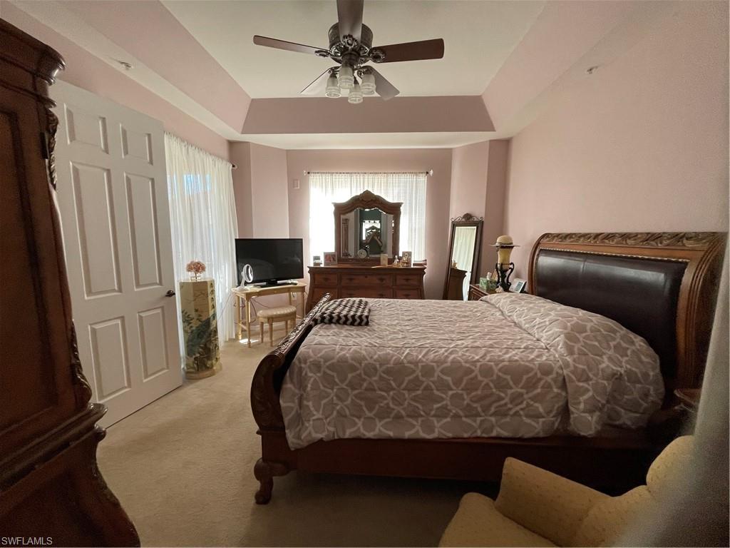 Carpeted Master bedroom featuring ceiling fan and a tray ceiling