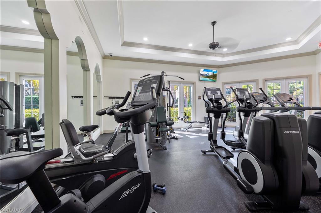 Gym with ornamental molding, a tray ceiling, and plenty of natural light