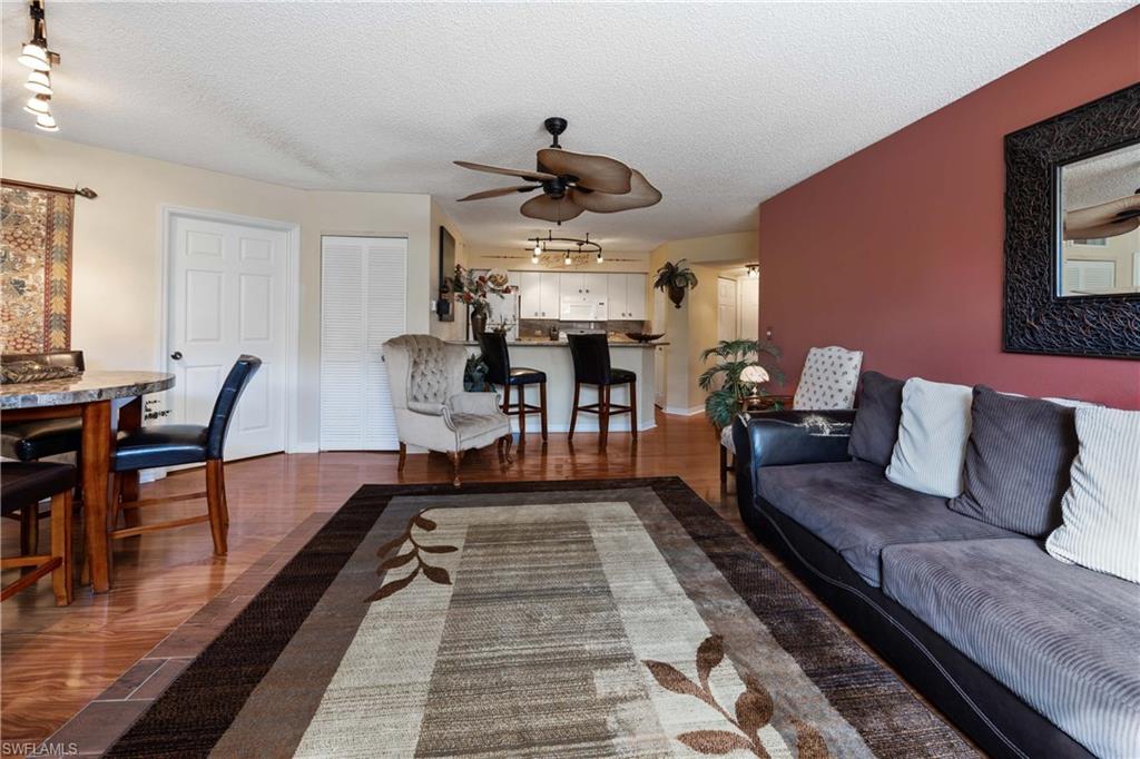 Living room with rail lighting, ceiling fan, a textured ceiling, and dark hardwood / wood-style floors