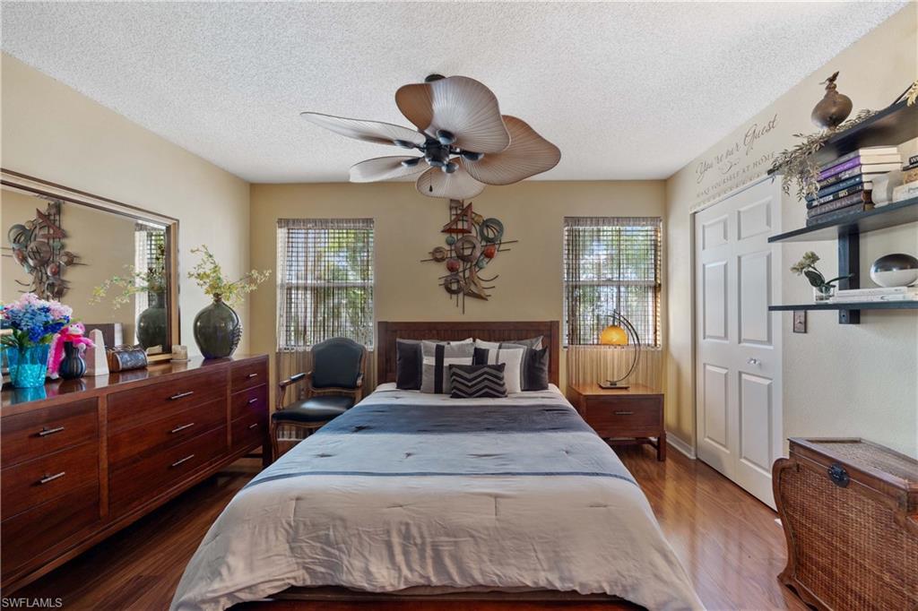Bedroom featuring a closet, ceiling fan, hardwood / wood-style flooring, and multiple windows