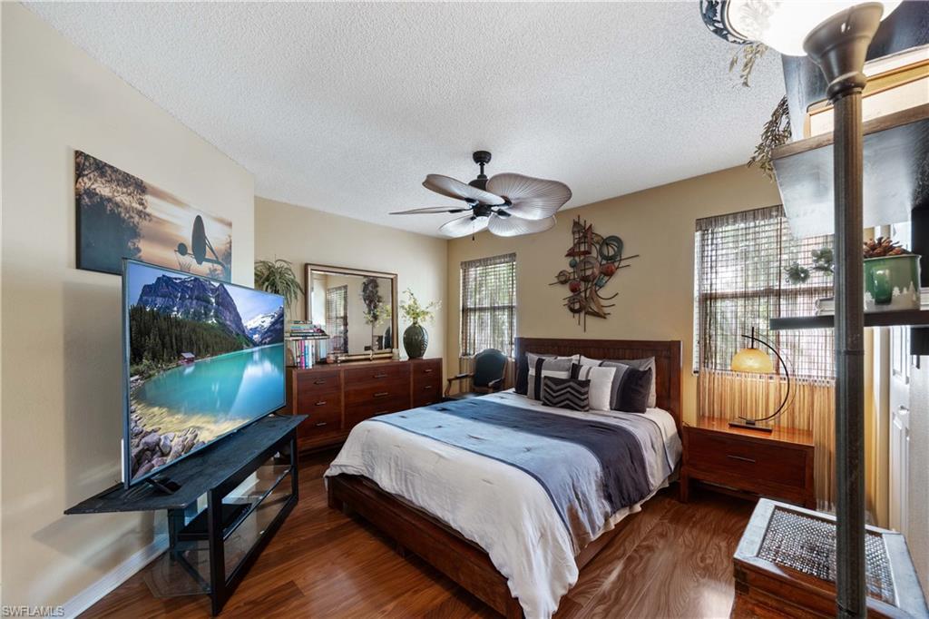 Bedroom featuring a textured ceiling, ceiling fan, multiple windows, and dark hardwood / wood-style flooring