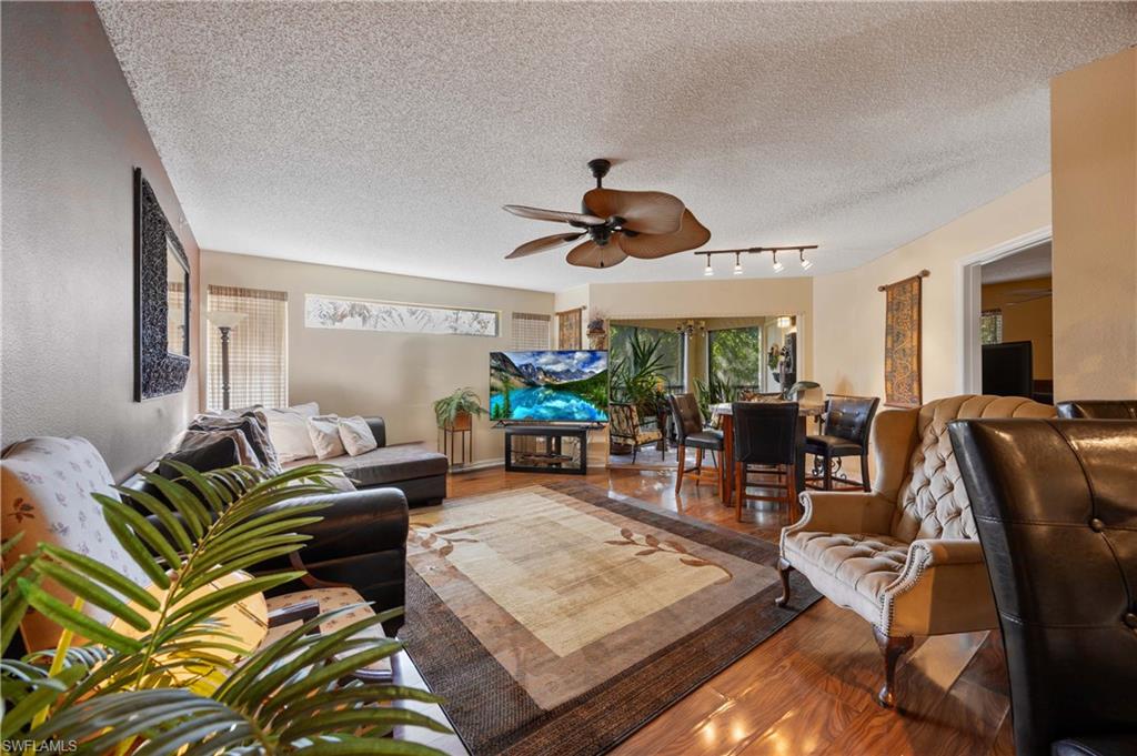 Living room featuring a textured ceiling, track lighting, hardwood / wood-style flooring, and ceiling fan