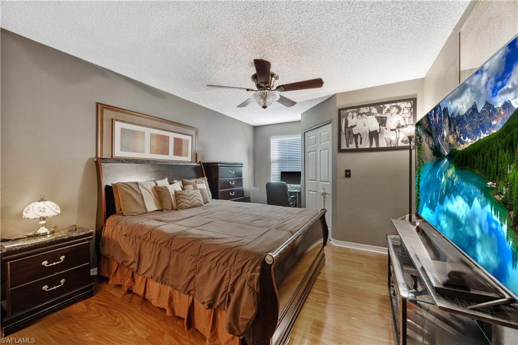 Bedroom featuring light hardwood / wood-style floors, a closet, a textured ceiling, and ceiling fan
