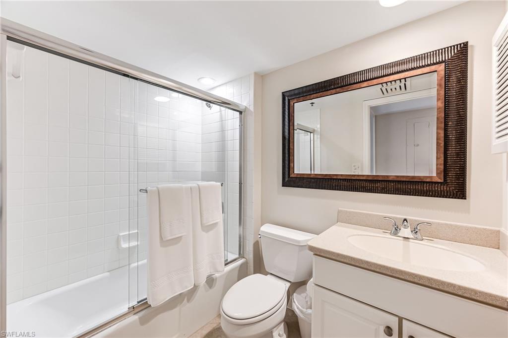 Full bathroom with vanity, toilet, and bath / shower combo with glass door