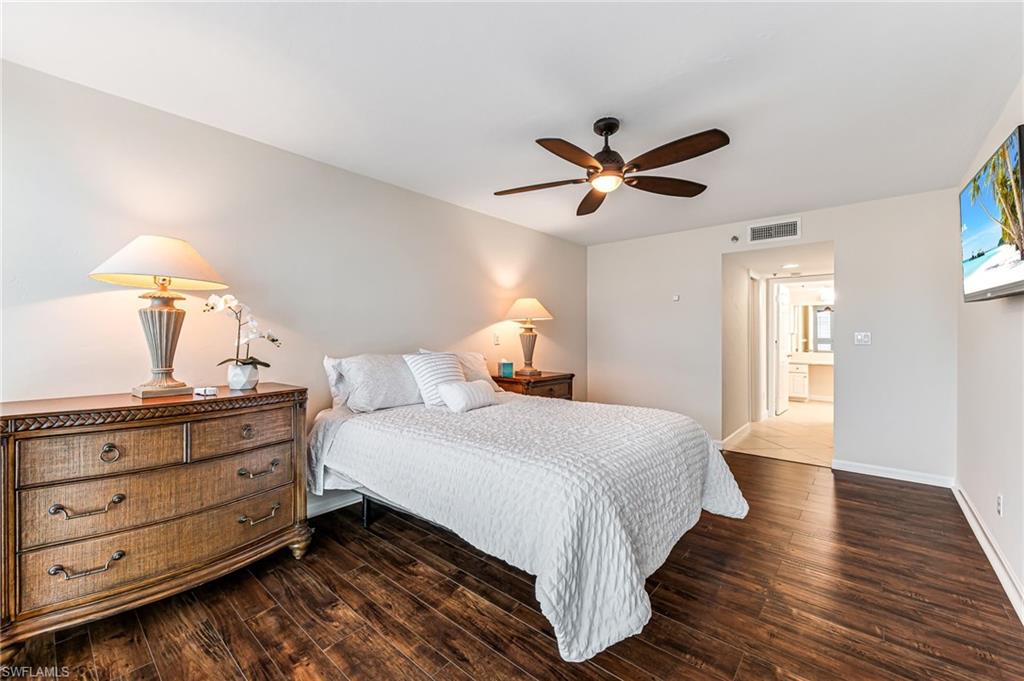 Bedroom with ceiling fan, ensuite bathroom, and dark hardwood / wood-style floors