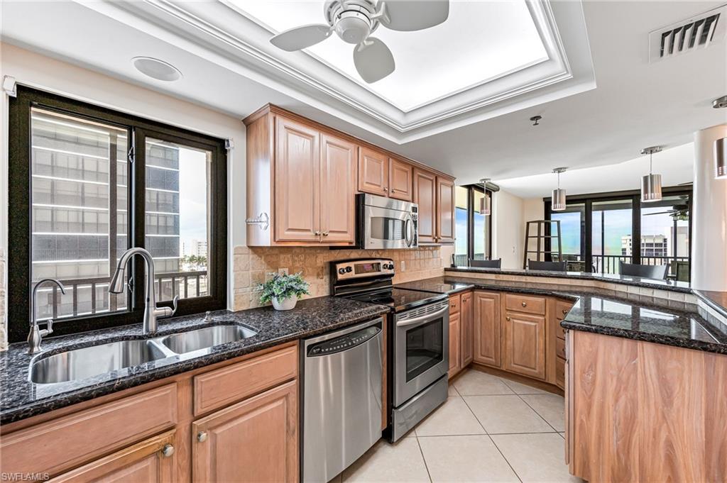 Kitchen featuring dark stone counters, sink, light tile patterned flooring, appliances with stainless steel finishes, and tasteful backsplash