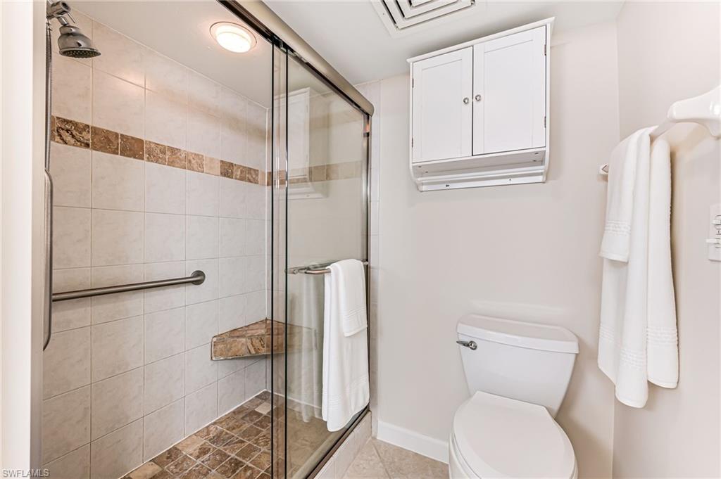 Bathroom featuring a shower with door and toilet
