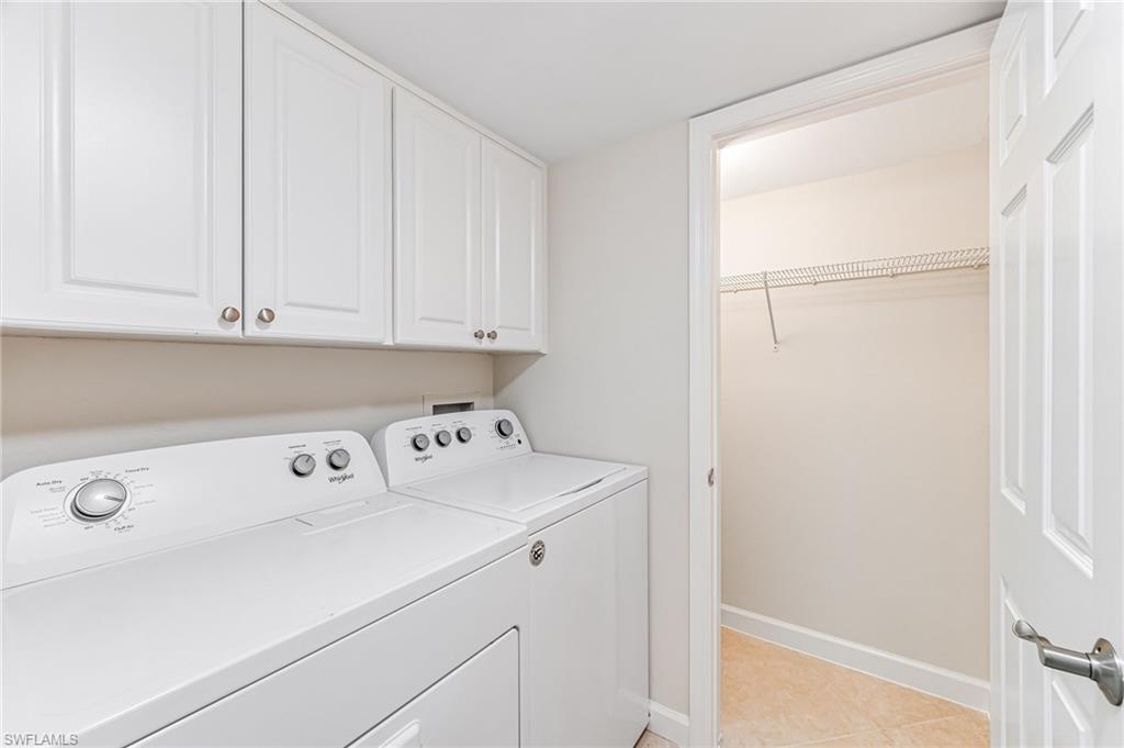 Laundry room featuring independent washer and dryer, light tile patterned flooring, and cabinets