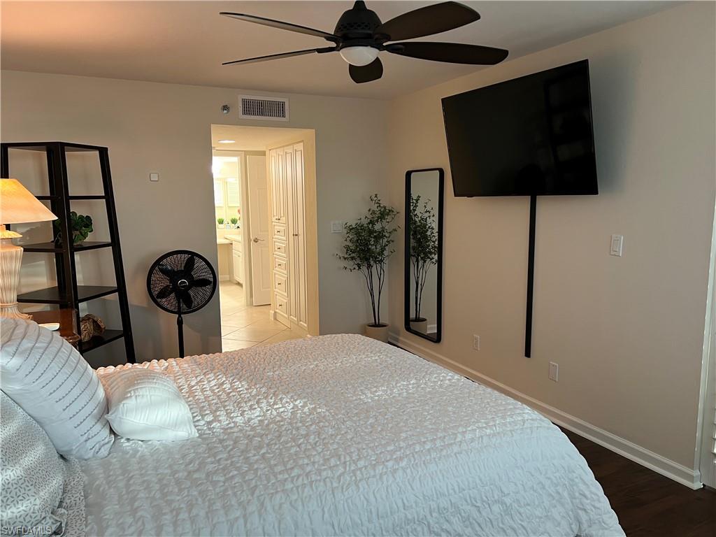 Bedroom with ceiling fan, connected bathroom, and hardwood / wood-style flooring