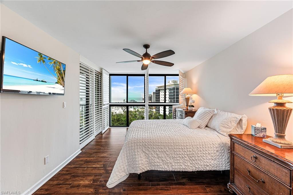 Bedroom featuring ceiling fan, dark hardwood / wood-style flooring, and a wall of windows