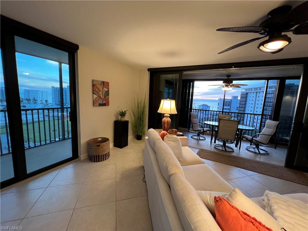 Tiled living room with ceiling fan and floor to ceiling windows