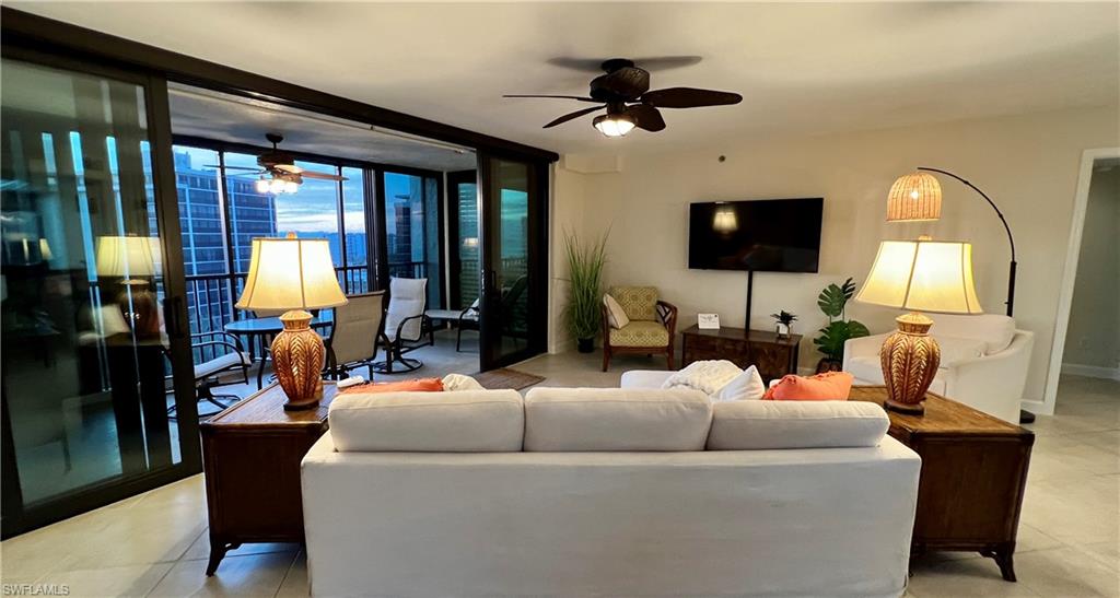 Living room with floor to ceiling windows, tile patterned floors, and ceiling fan